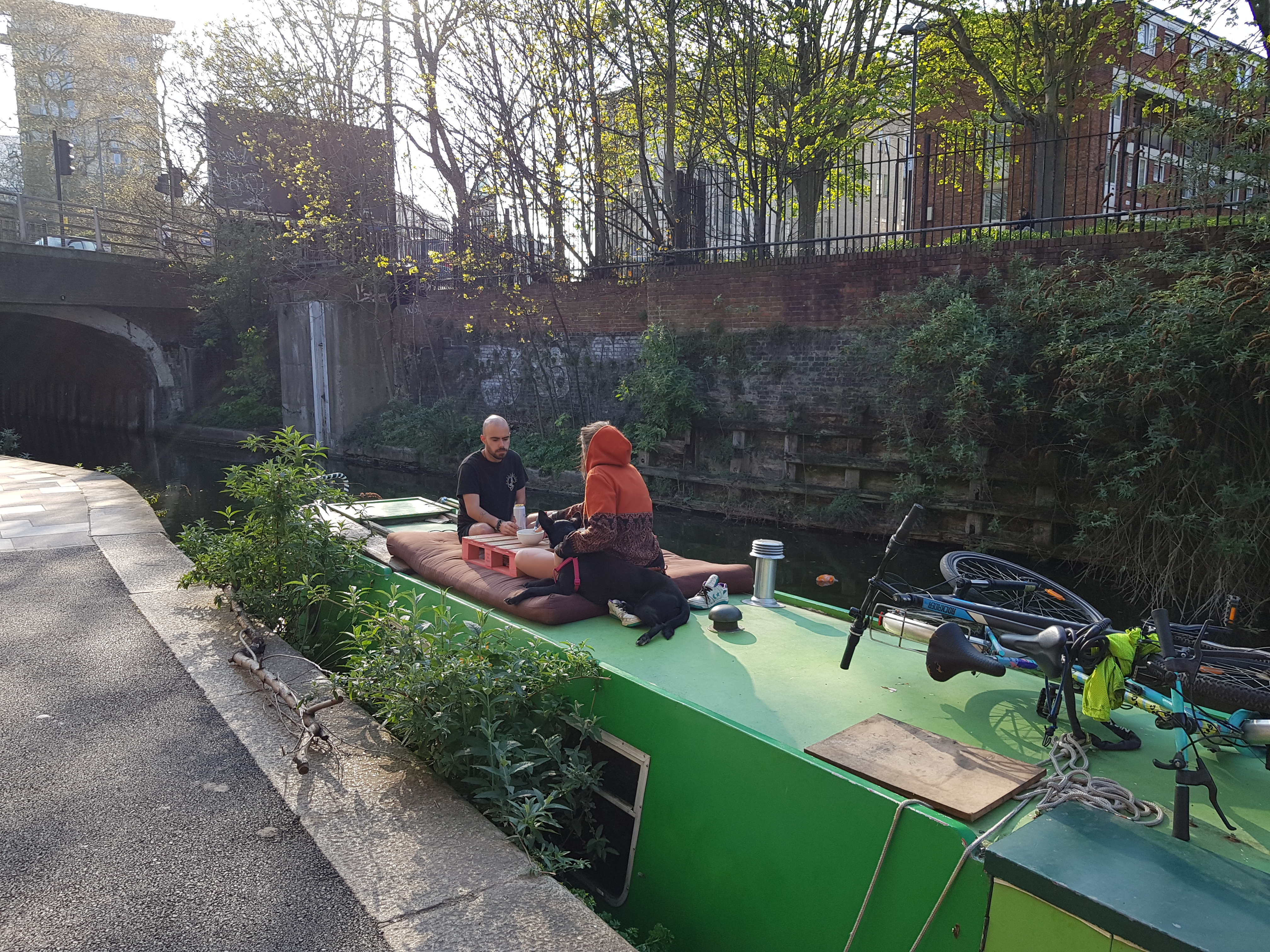 Couple eating lunch on top of barge in canal, Docklands, London